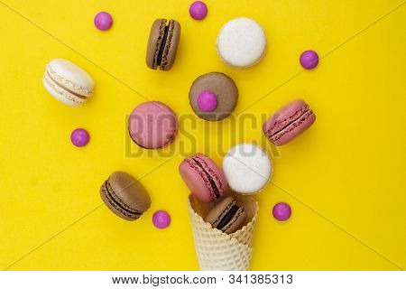 Macarons Cakes. Stil Life Photo Of Waffle Cone With Macaroons On Yellow Background. Flat Lay, Desser