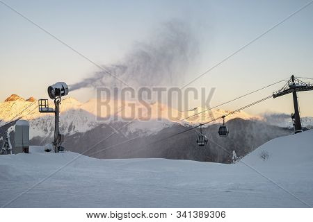 Snow Cannon On The Background Of Evening Mountains And Cable Car. Preparation For The Ski Season