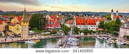 Lindau, Germany. Antique Bavarian town in Bavaria at coastline of Lake Constance (Bodensee). Habour along embankment with traditional houses and tower. Sunset evening landscape.