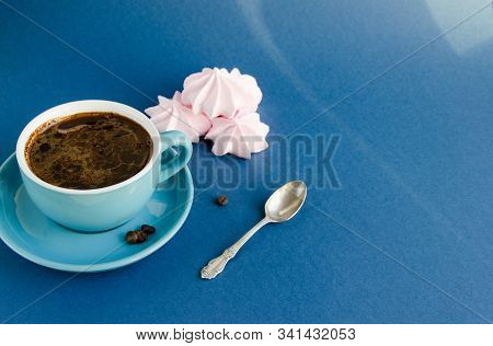 American Coffee In A Blue Cup On A Classic Blue Background. In The Background Lies Pink Meringue.