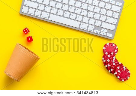 Hazard Gemes Online Concept. Poker Chips, Dices, Cup For Dice Near Keyboard On Yellow Background Top