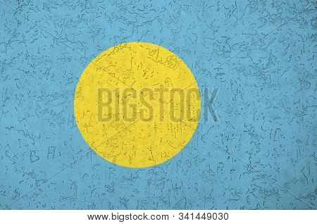Palau Flag Depicted In Bright Paint Colors On Old Relief Plastering Wall. Textured Banner On Rough B