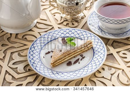 Slice Of Layered Honey Cake With Cup Of Tea On Oriental Wooden Table
