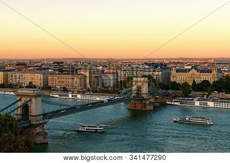 Scenic Evening View Of Budapest. One Of The Main Attractions Is Ancient Chain Bridge Over Danube Riv