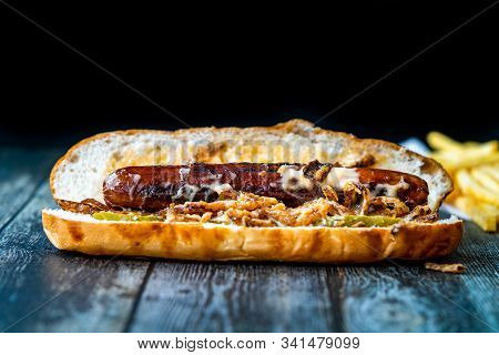 Hot Dog With Caramelized Onion, Cheddar And Gruyere Cheese Sauce On Wooden Surface With Potatoes.