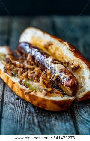 Hot Dog With Caramelized Onion, Cheddar And Gruyere Cheese Sauce On Wooden Surface With Potatoes.