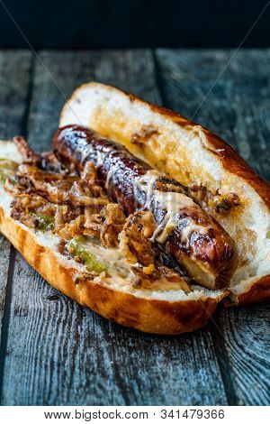 Hot Dog With Caramelized Onion, Cheddar And Gruyere Cheese Sauce On Wooden Surface With Potatoes.