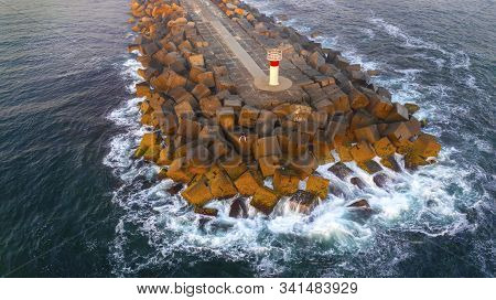 Aerial View Of A Person Sitting On The Gold Coast Spit Breakwall, With The Ocean Washing Over The Ro