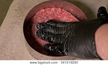 Cook Makes Meat Medallions For Burgers. Chef In Black Food Gloves Makes Cutlet. Cutlets Are Leveled 