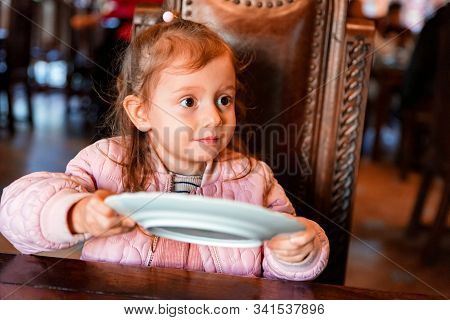 Cute Preschooler Girl Asks For Food With Empty Plate In Hands