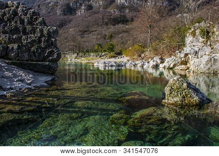 Limpid Mountain Stream Flows Cold Among Millennial Rocks Of The Vicenza Alps Carved Out By Time In C