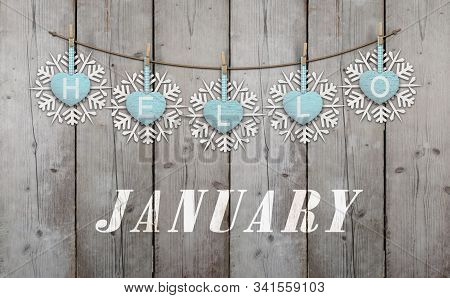 Hello January Written On Hanging Ice Blue Hearts And White Wooden Snowflakes On Weathered Planks Bac