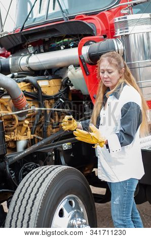 Woman Truck Driver Checking The Oil Level On A Big Truck