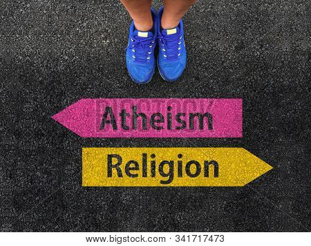 Men With A Shoes Are Standing On Asphalt Next To Arrow Signs Of Words Atheism And Religion