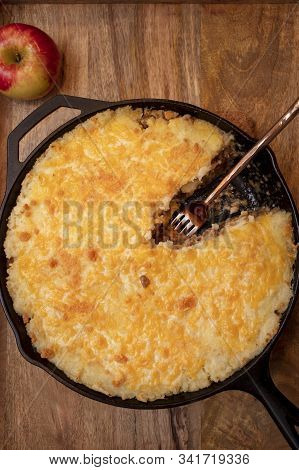 Shephers Pie Baked In A Cast Iron Skillet And Placed On A Wood Tray With An Apple And Napkins