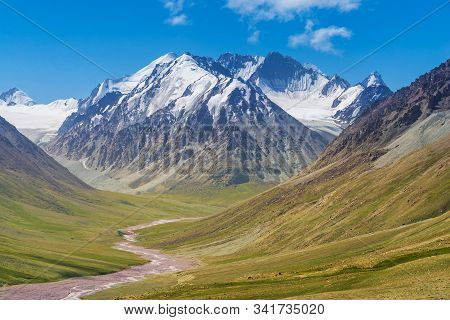 Majestic Snow Capped Mountains Or Glacier Landscape With Green Alpine Meadows And Stream Running In 