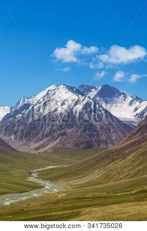 Majestic Snow Capped Mountains Or Glacier Landscape With Green Alpine Meadows And Stream Running In 