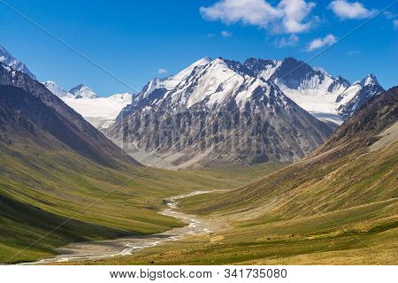 Majestic Snow Capped Mountains Or Glacier Landscape With Green Alpine Meadows And Stream Running In 