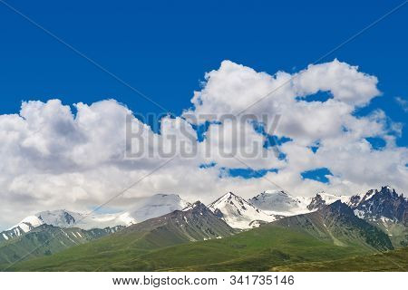 Cloudscape Majestic Snow Capped Mountains Or Glacier And Green Alpine Meadows Under Cloudy Blue Sky 
