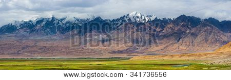 Panoramic View Of Majestic Landscape In The Pamirs Plateau With Fresh Green Meadows And Snow-capped 
