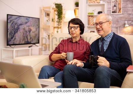 Elderly Old Couple Using Modern Laptop To Chat With Their Grandson