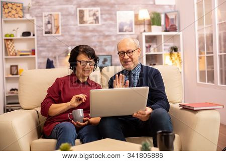 Elderly Old Couple Using Modern Laptop To Chat With Their Grandson