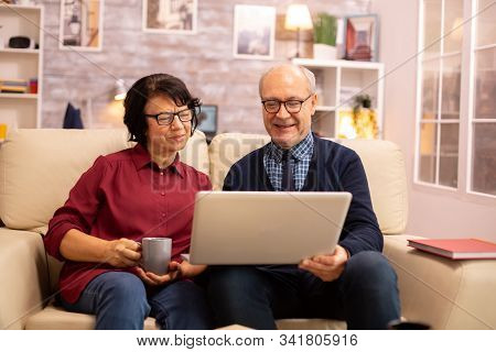 Elderly Old Couple Using Modern Laptop To Chat With Their Grandson