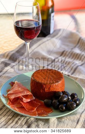 Tastes Of Spain, Jamon Iberian, Black Olives, Manchego Cheese With Red Paprika And Glass With Red Ri
