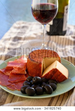 Tastes Of Spain, Jamon Iberian, Black Olives, Manchego Cheese With Red Paprika And Glass With Red Ri