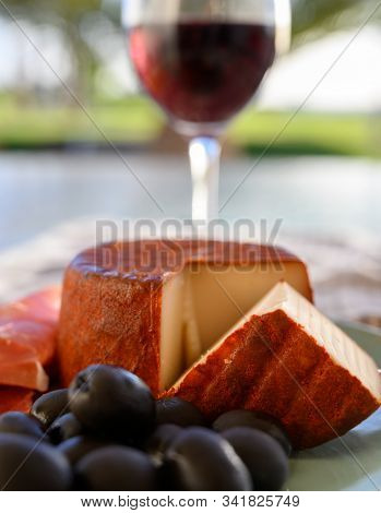 Tastes Of Spain, Jamon Iberian, Black Olives, Manchego Cheese With Red Paprika And Glass With Red Ri