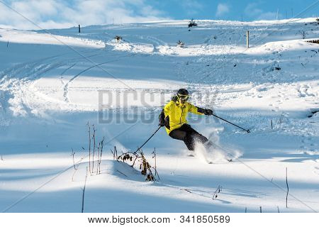 Skier In Helmet Holding Ski Sticks While Skiing On Slope Outside