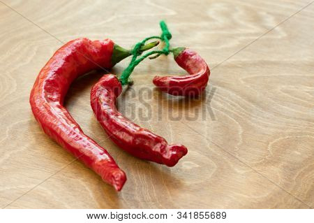 Dried Red Hot Chili Pepper As Spicy Flavoring For Meal. A Group Of Bright Red Thai Chili Peppers Wit