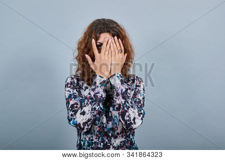 Charming Brunette Caucasian Young Woman Covered Face With Hands, Looking Through It Over Isolated Gr
