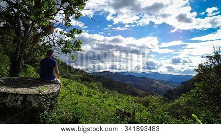 Man Sitting On A Rock Looking At A Ecuadorian Beautiful Landscape. Panoramic View From The Sierra. C