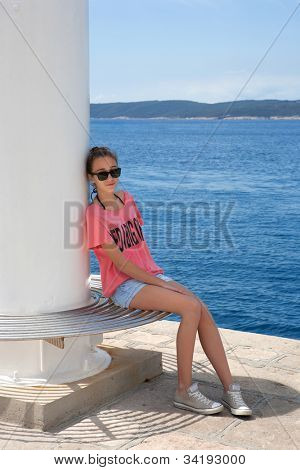 Adolescente, assis au bord de la mer