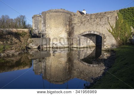 Reflections Of The Ramparts At Bergues, Northern France, Against A Blue Sky.