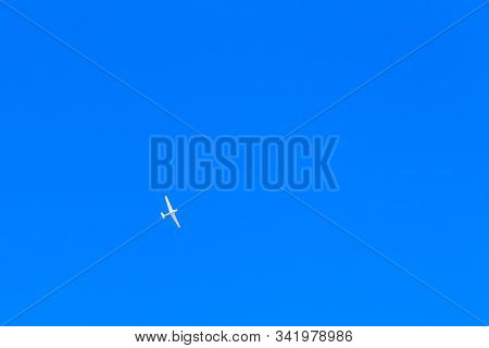 A White Sports Plane Flies In A Bright Blue Cloudless Sky. Concept: Sport, Dream, Peace, Romance.
