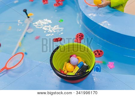 Fishing In The Paddling Pool. Childrens Toys In The Pool. Toy Fish Fishing Rod. Cheerful Children Fi