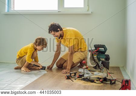 Father And Son Installing New Wooden Laminate Flooring On A Warm Film Floor. Infrared Floor Heating 