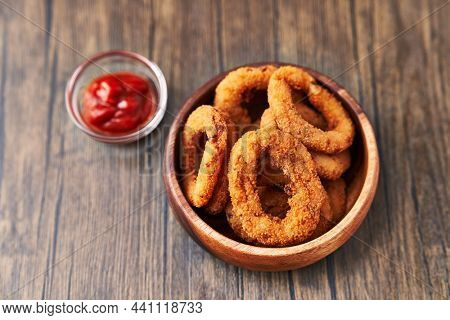  Bowl of breaded onion rings on a wooden surface