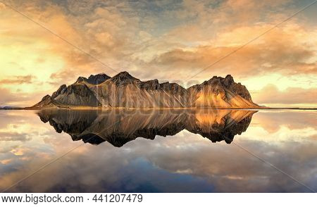 A panorama of sunset at Vestrahorn, Stokksnes peninsula. Golden hour shot with mirror reflection at dusk. South-east Iceland in autimn. 