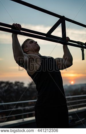 Muscular Man Doing Pullups On Sunset Sky Background. Concept Of Willpower, Motivation And Passion