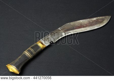 Kukri Knife On A Flat Black Table. Steel Arms