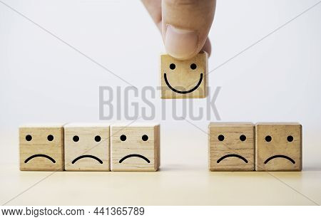 Hand Holding Smile Face Print Screen On Wooden Cube Block Among Sadness Face For Customer Service Ev