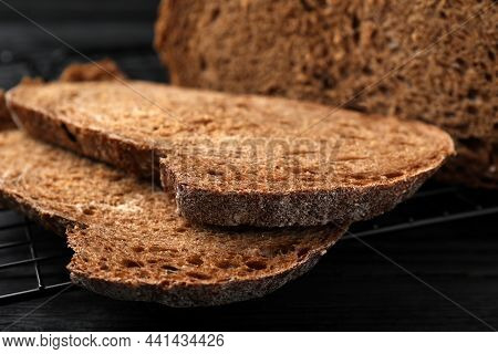 Cooling Rack With Slices Of Tasty Rye Sodawater Bread On Black Wooden Table, Closeup