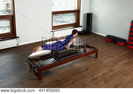 The Instructor Does Exercises On The Reformer, A Beautiful Girl Trains On The Modern Reformer Simula