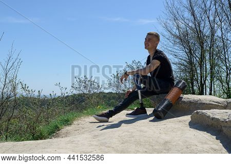 A Man On A Prosthetic Leg Travels The Mountains. Dressed In Black Jeans And A T-shirt