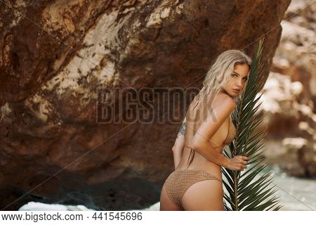 Sexy Beach Blonde Girl In Knitted Bikini With Palm Leaf Outdoors On Nature