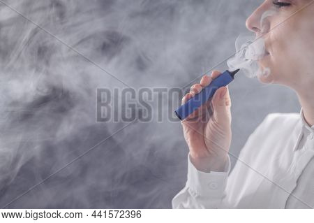 Caucasian Woman Smokes A Disposable Vape In The Studio.