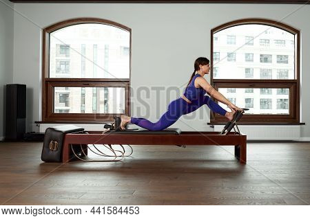The Instructor Does Exercises On The Reformer, A Beautiful Girl Trains On The Modern Reformer Simula